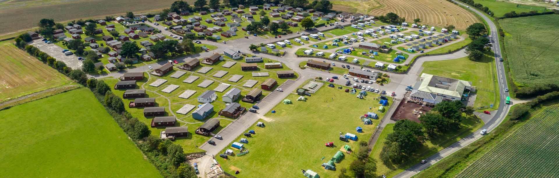 Aerial view of Atlantic Bays Holiday Park — lodges, touring field and facilities among the St Merryn farmland near Padstow