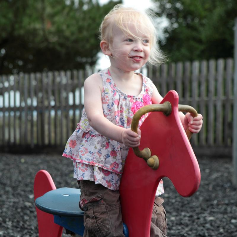 Smiling toddler on a red spring rocker in the refurbished play area at Atlantic Bays Holiday Park