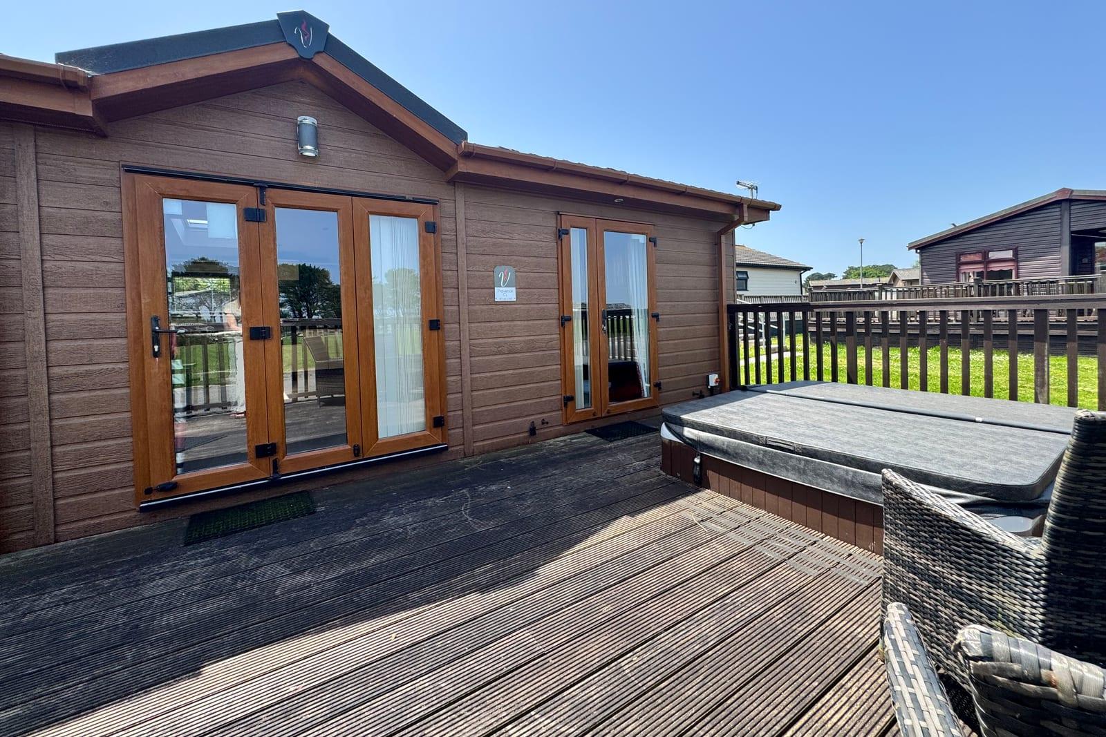 Private decking and hot tub outside a lodge at Atlantic Bays Holiday Park
